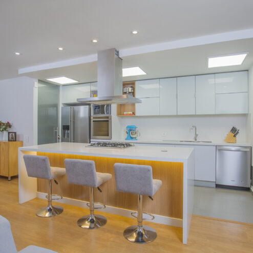 Cocina contemporánea de concepto abierto, con isla central, iluminación integrada y una paleta clara que potencia la funcionalidad y la amplitud del espacio